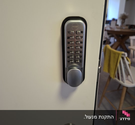 מנעול דלת עם לוח מקשים על דלת לבנה